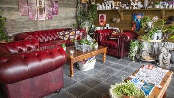Una sala de estar acogedora con sofás de cuero rojo, una mesa de centro de madera y varios objetos decorativos, como plantas y obras de arte.