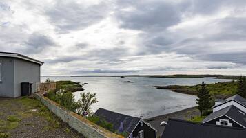 A coastal view with a house, a car, and a body of water.