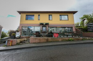 Un edificio con fachada amarilla, un cartel que indica el alojamiento 'Kattfjorod', y una entrada visible con escalones.