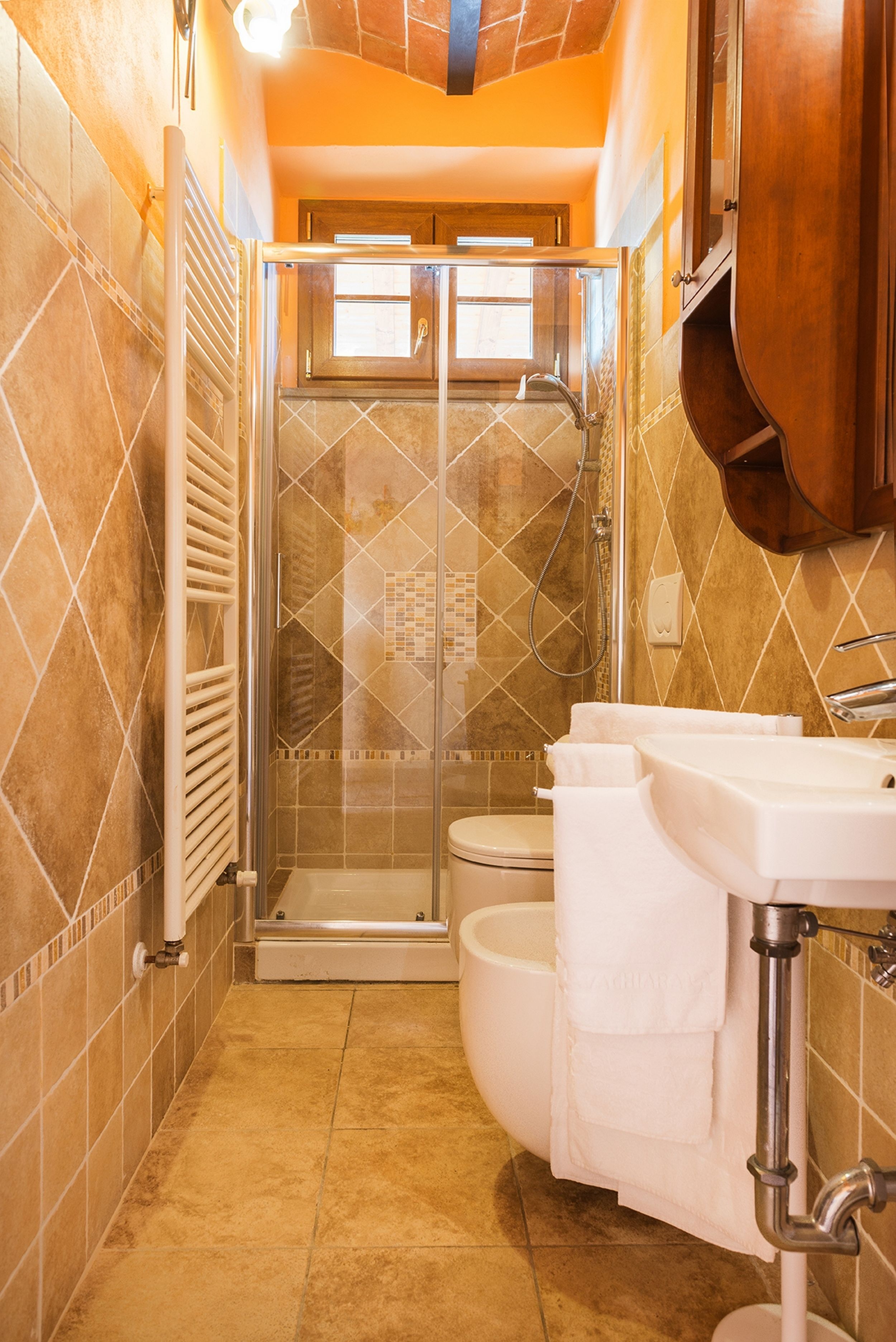 A bathroom with a glass-enclosed shower, a toilet, and a sink with a towel.