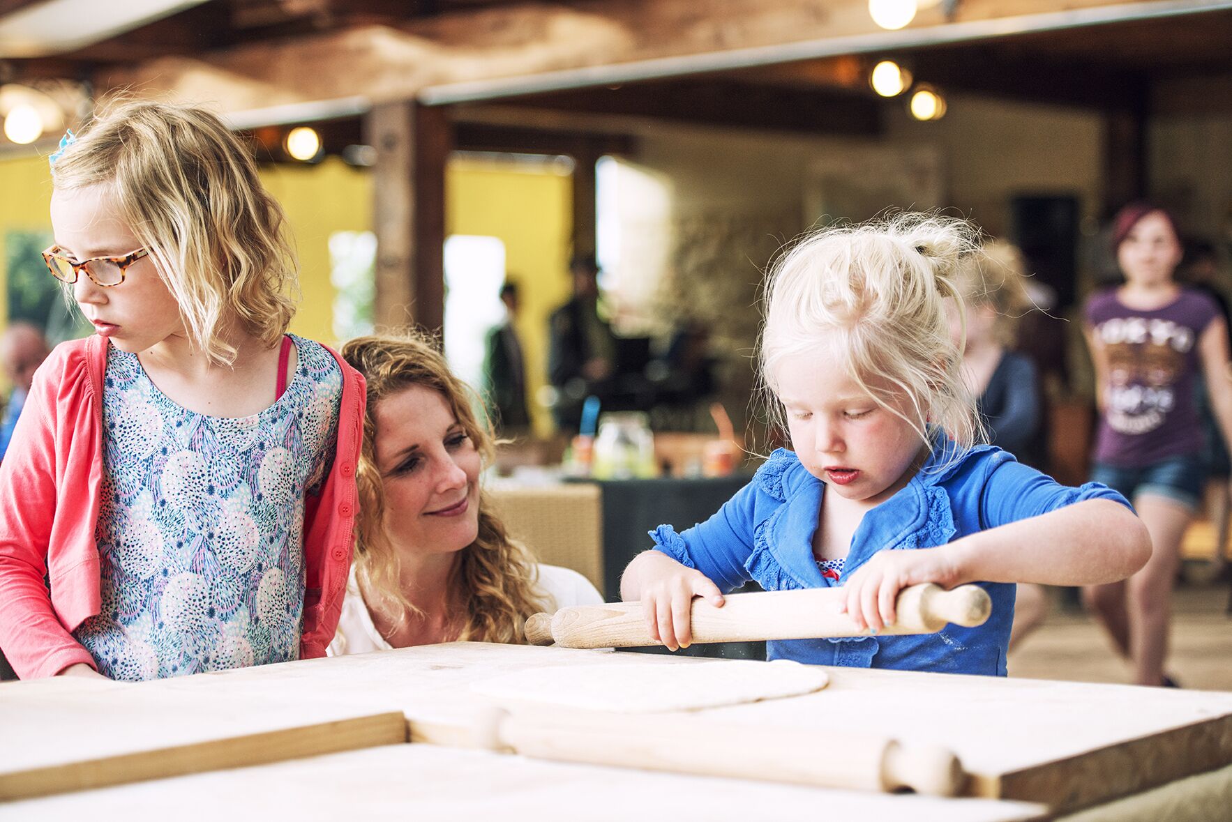 A group of people engaged in an activity at a table with rolling pins and dough.