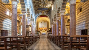 A church interior with a checkered floor, wooden pews, and marble columns. - Agriturismo Panieracci (Volterra)