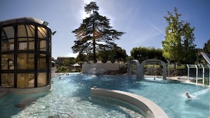 A swimming pool with clear water, surrounded by a glass structure and trees. - Agriturismo Panieracci (Volterra)