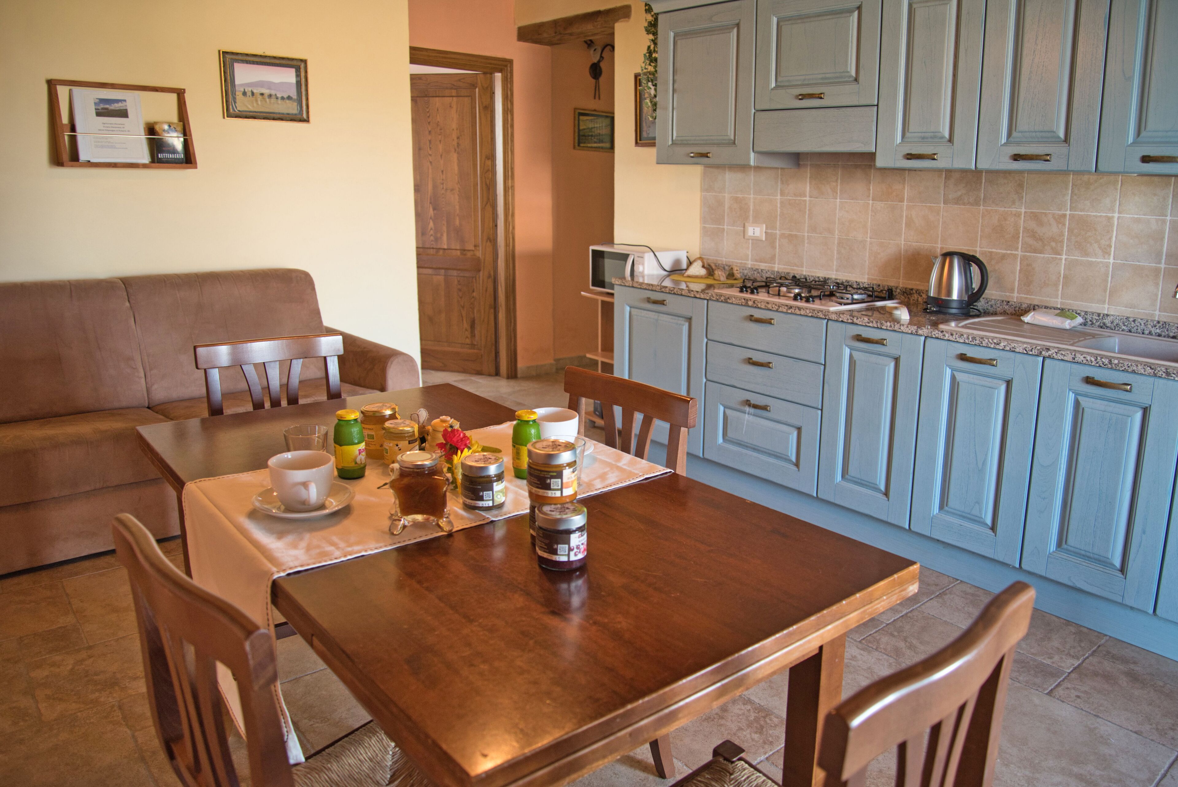 Un coin repas avec une table en bois, des chaises et une cuisine en arrière-plan.