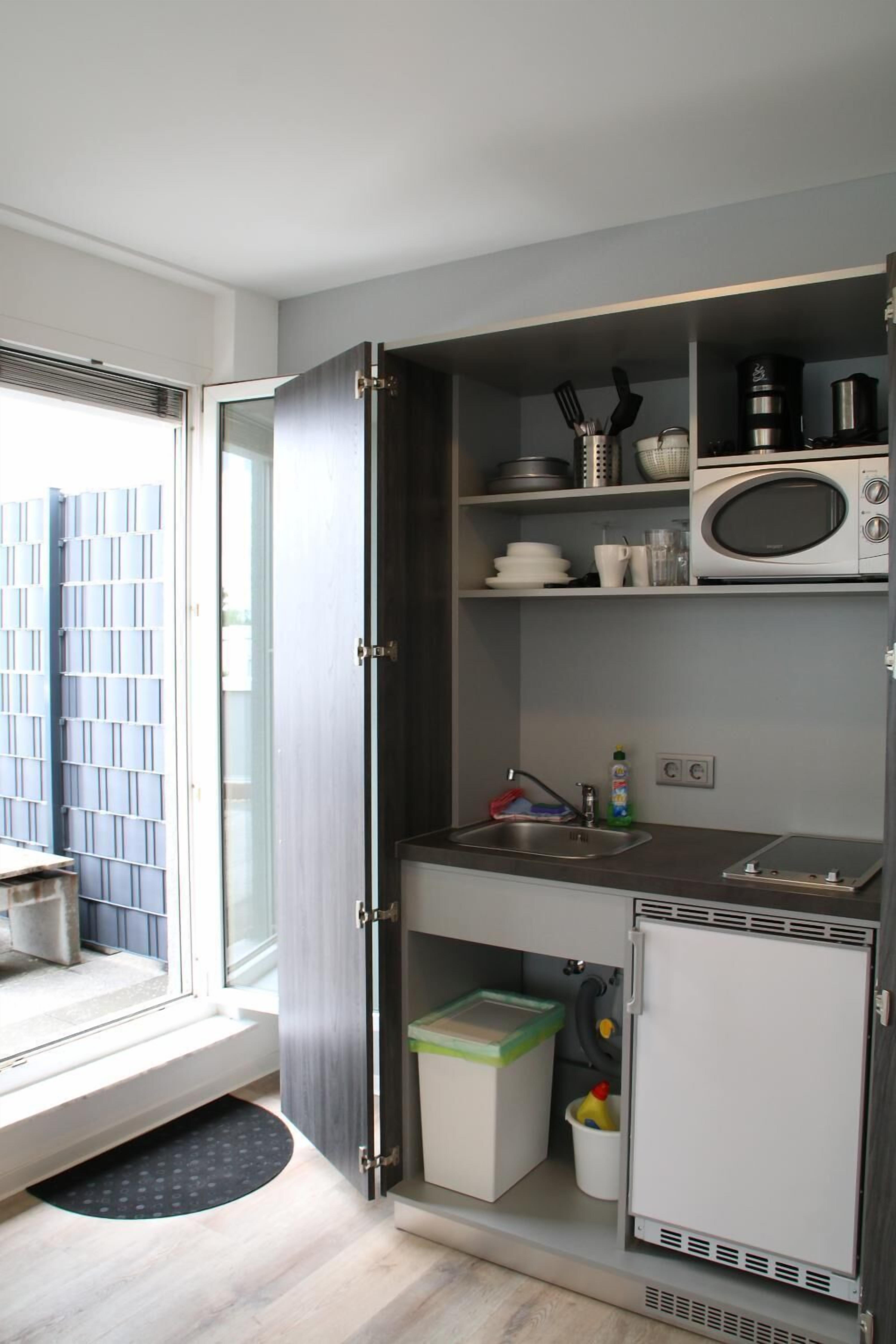 A compact kitchen with a microwave, sink, and storage cabinets.