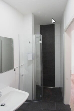 Un baño moderno con cabina de ducha de vidrio, un lavabo blanco y un espejo.