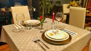Una mesa para dos, con mantel de lunares, platos, cubiertos y una vela.