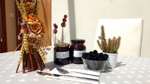 Una mesa con dos tarros de conservas, un cactus en maceta, un bol de moras y un arreglo floral.