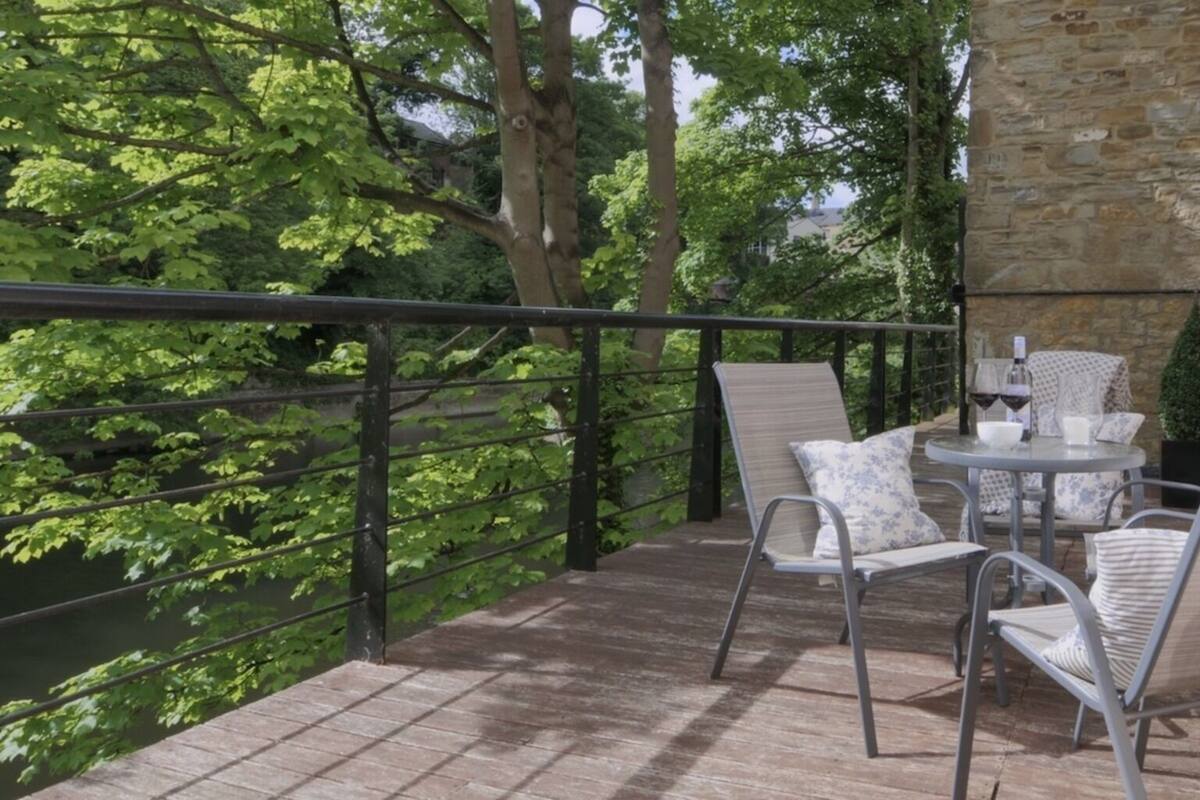 A balcony with a stone wall, metal railing, and a table with chairs.