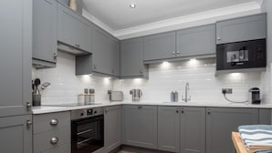 A modern kitchen with grey cabinets, a built-in oven, a microwave, and a sink. - Durham Riverside Apartments (Durham)