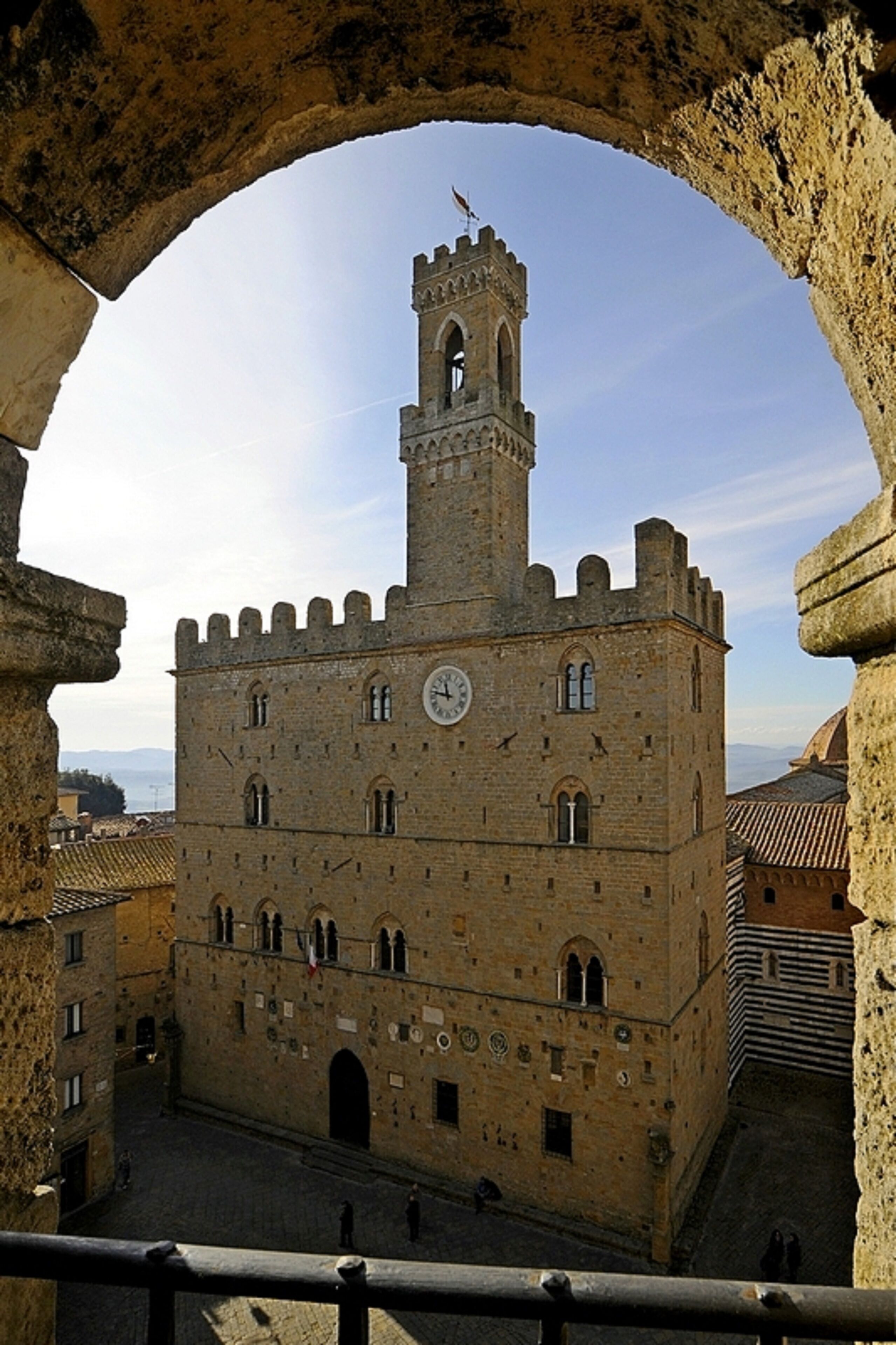 A historic building with a clock tower, arched entrance, and a courtyard.