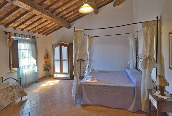 A bedroom with a four-poster bed, a wooden ceiling, and a large window with curtains. - Agriturismo Pelagaccio (Peccioli)