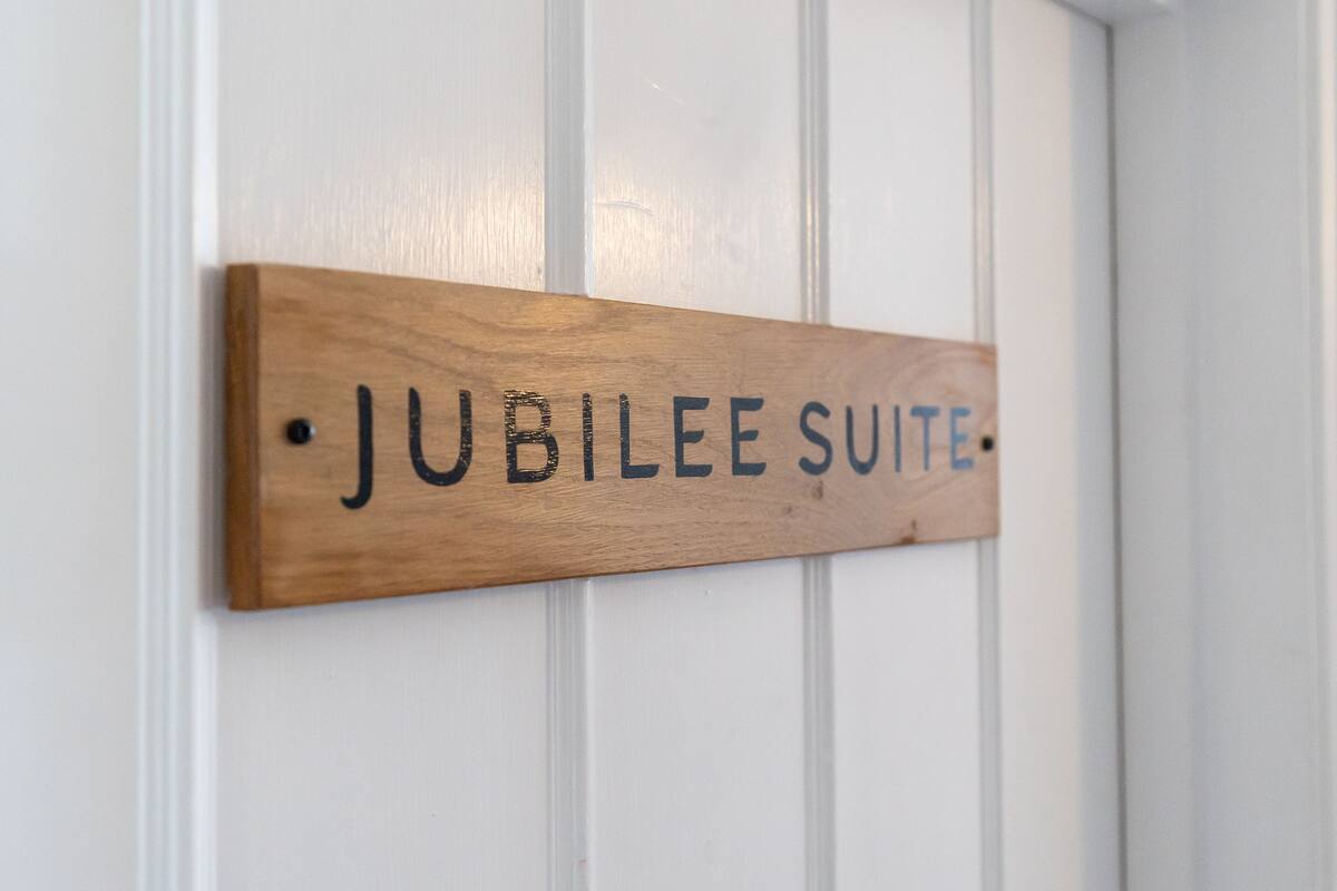 A wooden sign with the text "Jubilee Suite" mounted on a white door.