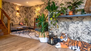 A living room with a sofa, a coffee table, a potted plant, a tiger statue, and a staircase. - The Godolphin (Marazion)