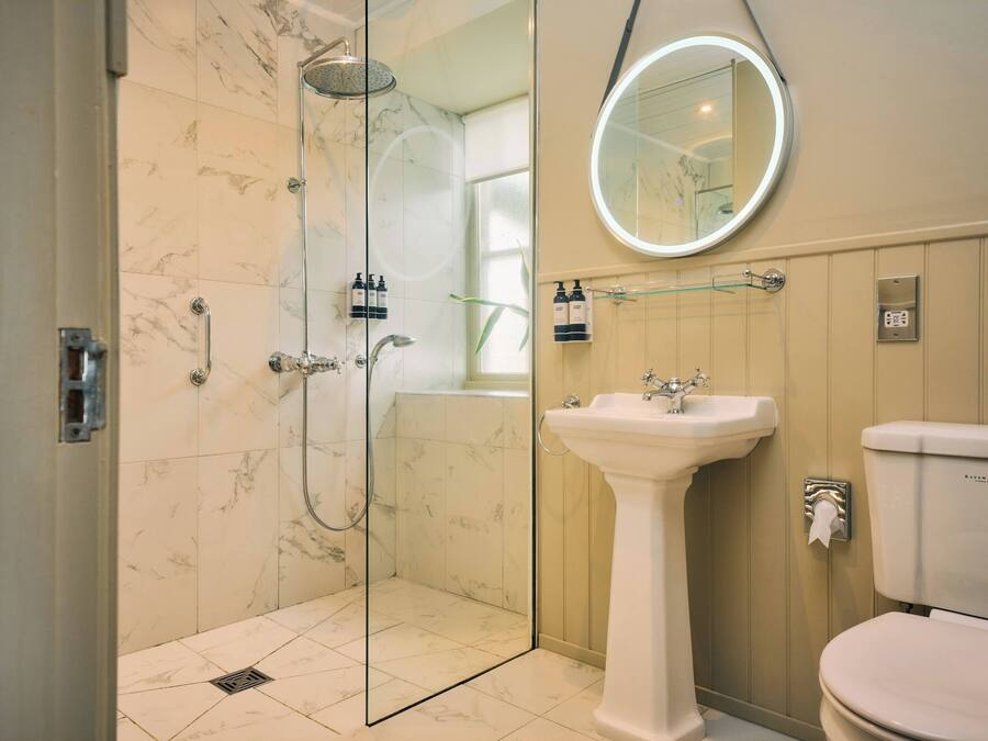 A bathroom with a glass-enclosed shower, a pedestal sink, and a toilet.