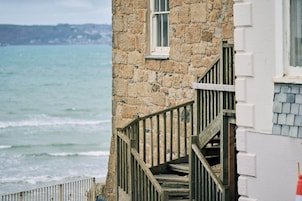 Un edificio de piedra con una escalera de madera que lleva a una ventana con vistas al mar.