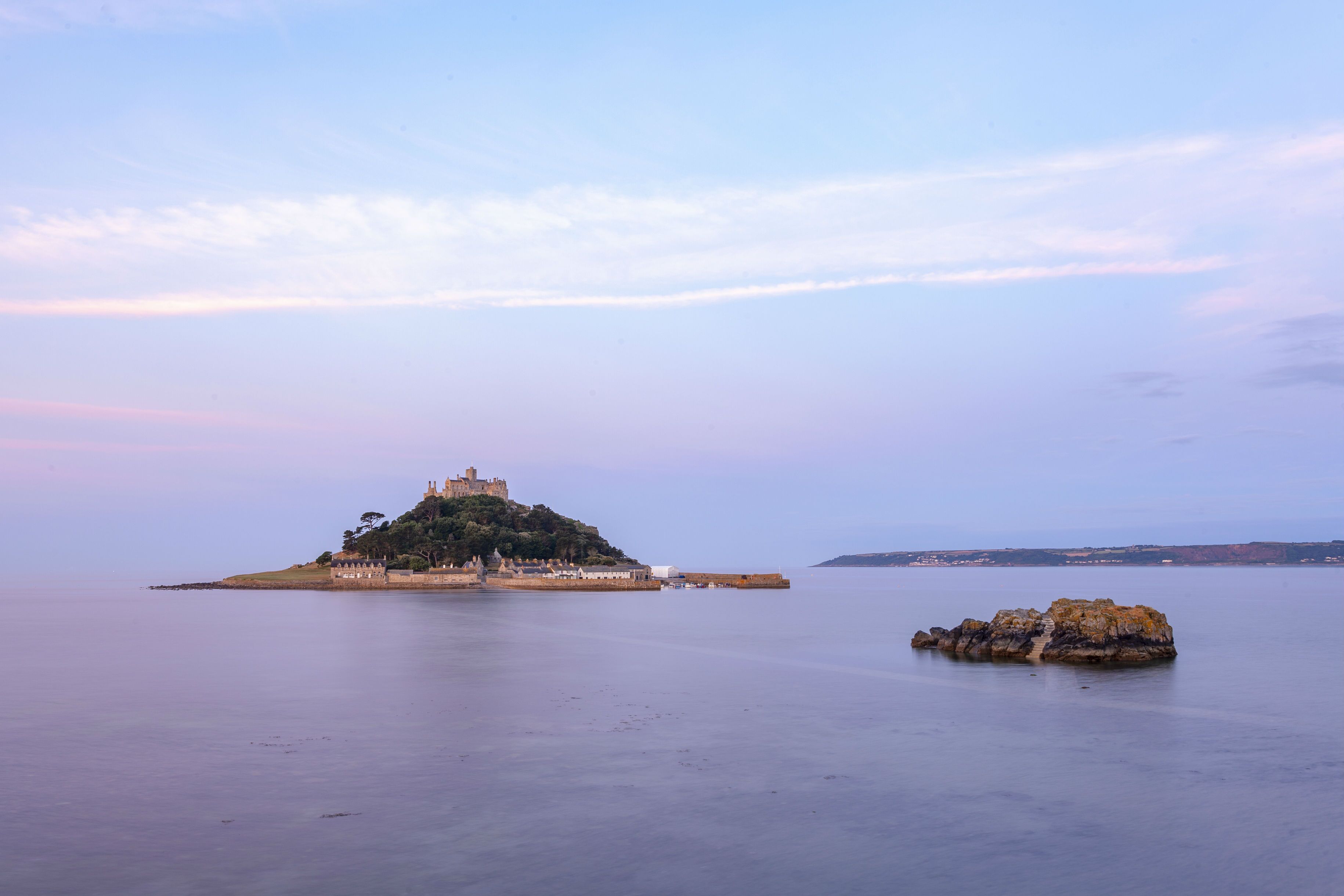 A castle on a hill overlooking calm water.