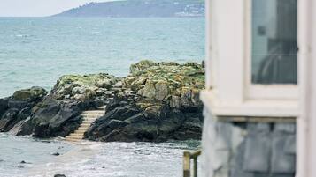 Vista costera con un edificio que tiene una escalera que conduce a un balcón con vistas al mar.