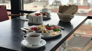 A dining table with plates of food, cups of tea, and a basket of bread.