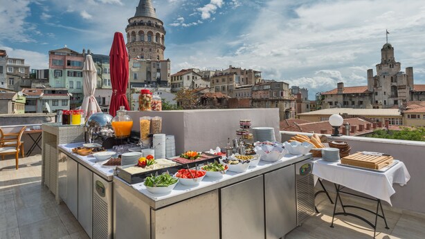A rooftop breakfast buffet with a variety of food items and a view of historic buildings in the background.