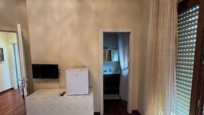 Een hotelkamer met een bed, een bureau, een televisie en een raam met gordijnen.