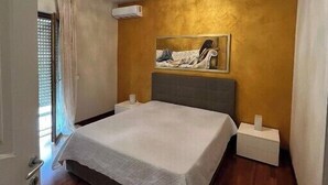 Een slaapkamer met een bed, nachtkastje, een wandairconditioner en een plafondlamp.
