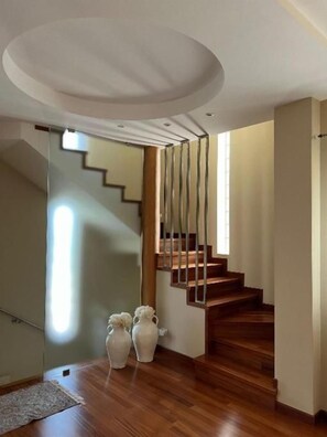 Una escalera de madera con barandilla de vidrio que lleva a un piso superior.