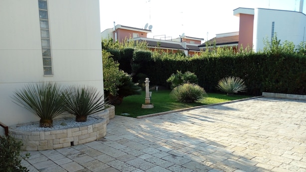 Een geplaveid binnenhof met een kleine tuin, een stenen muur en een beeld.