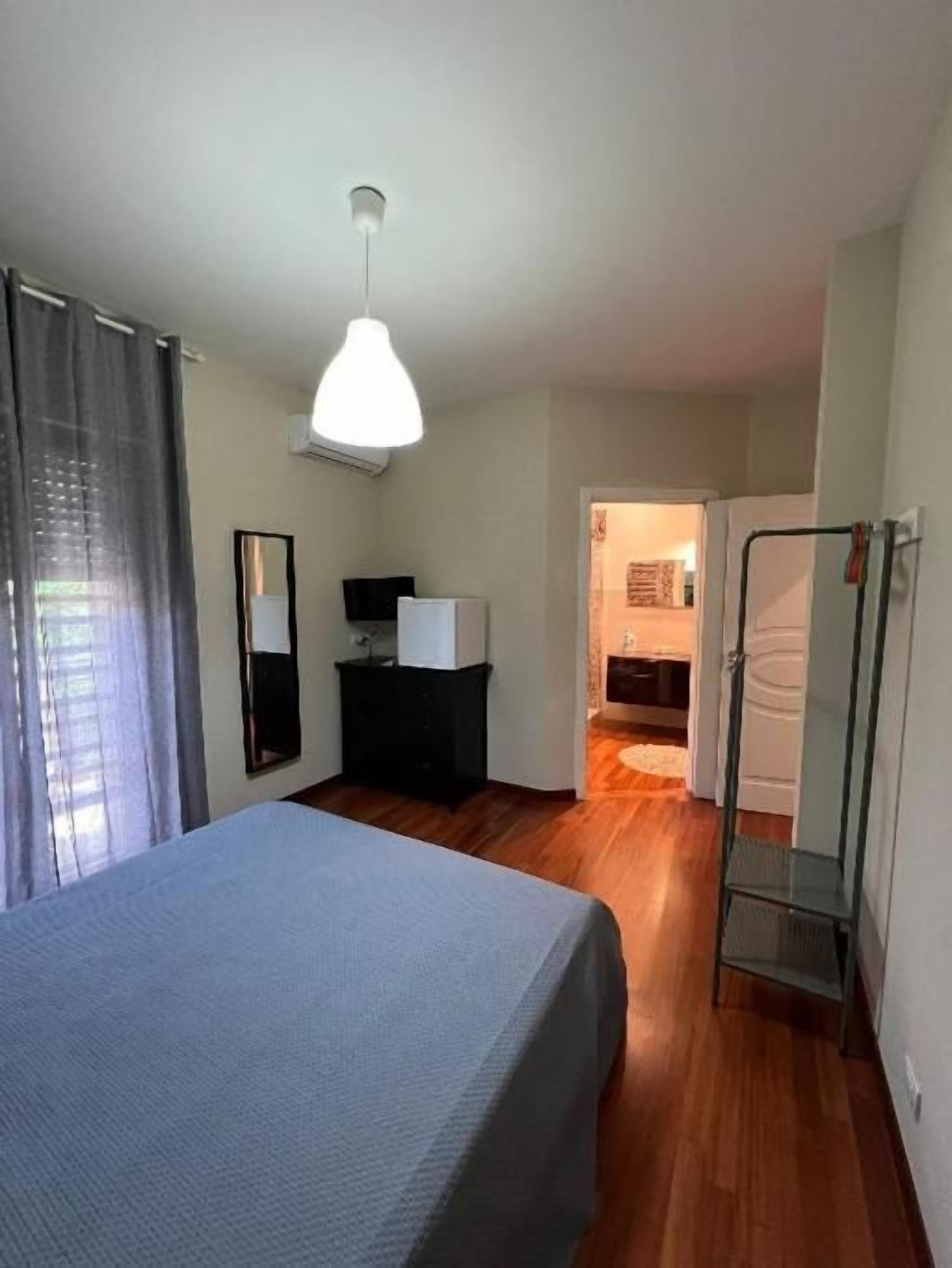 Un dormitorio con una cama, un armario, un espejo y una lámpara colgante.