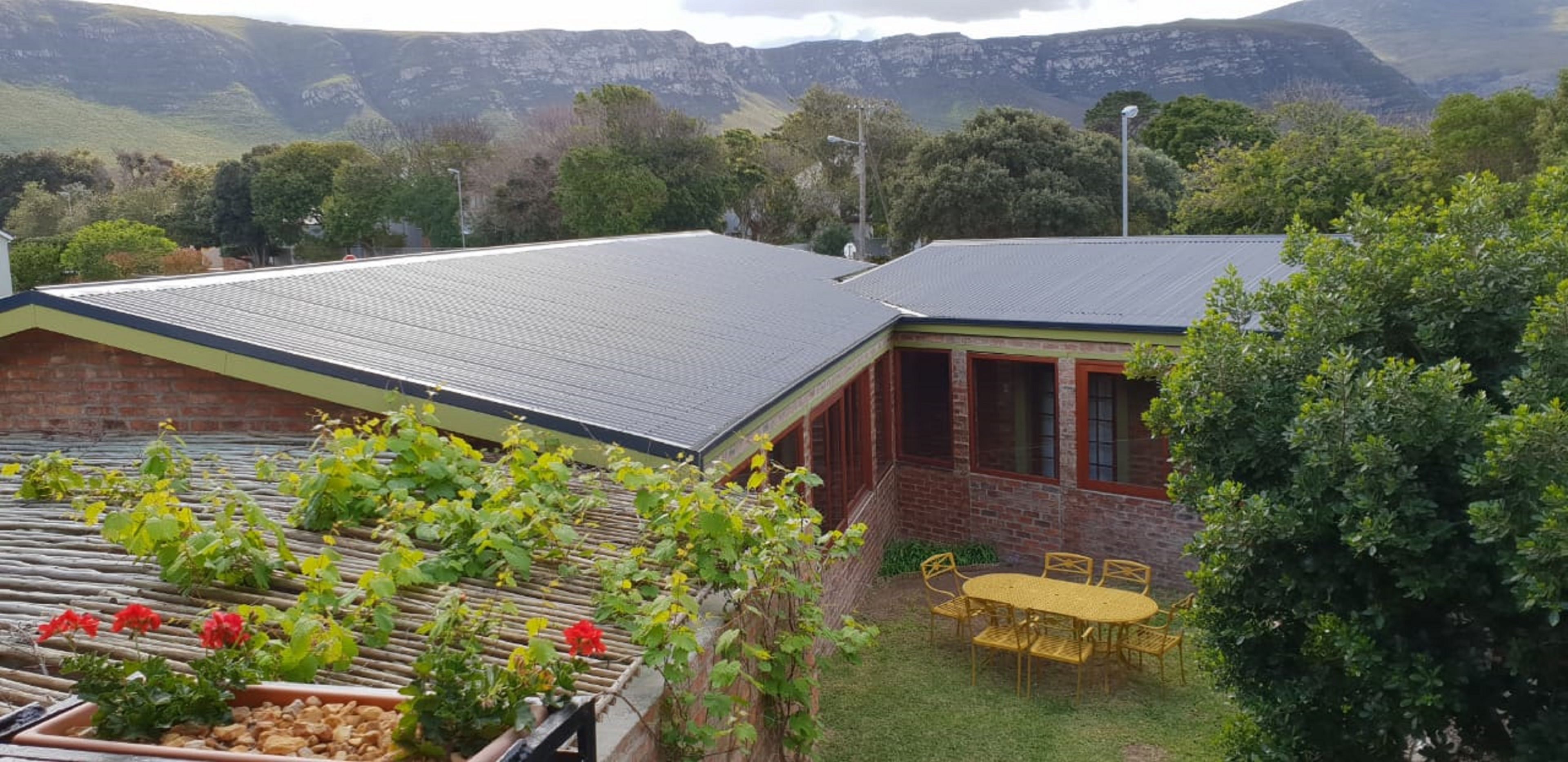 A building with a flat roof, a brick exterior, and a small patio with a table and chairs.