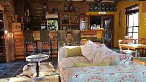 Un rincón acogedor de bar con muebles de madera, un sofá estampado y una exhibición de botellas.