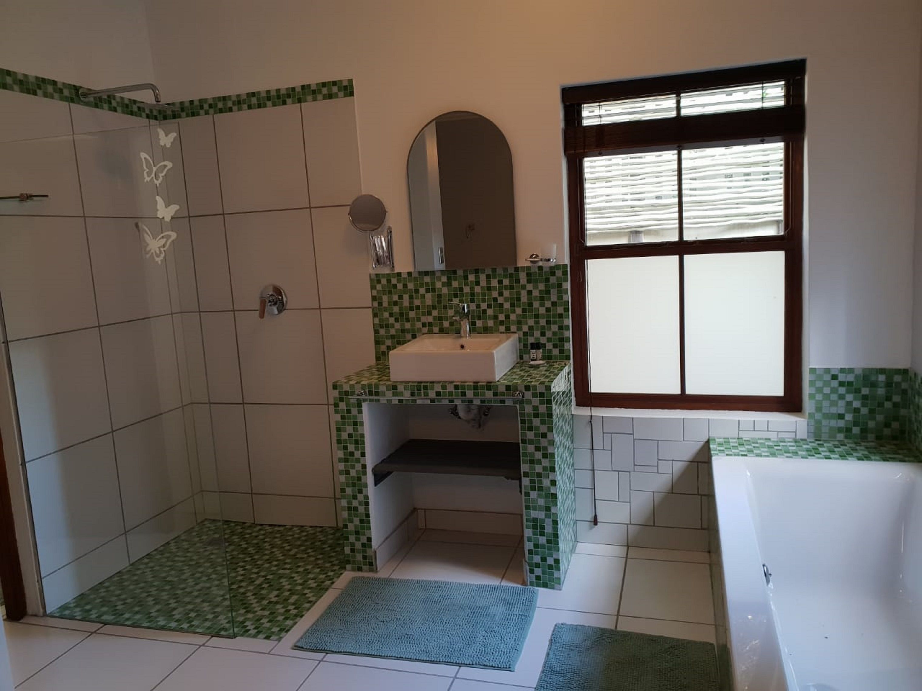 A bathroom with a shower, sink, and window.