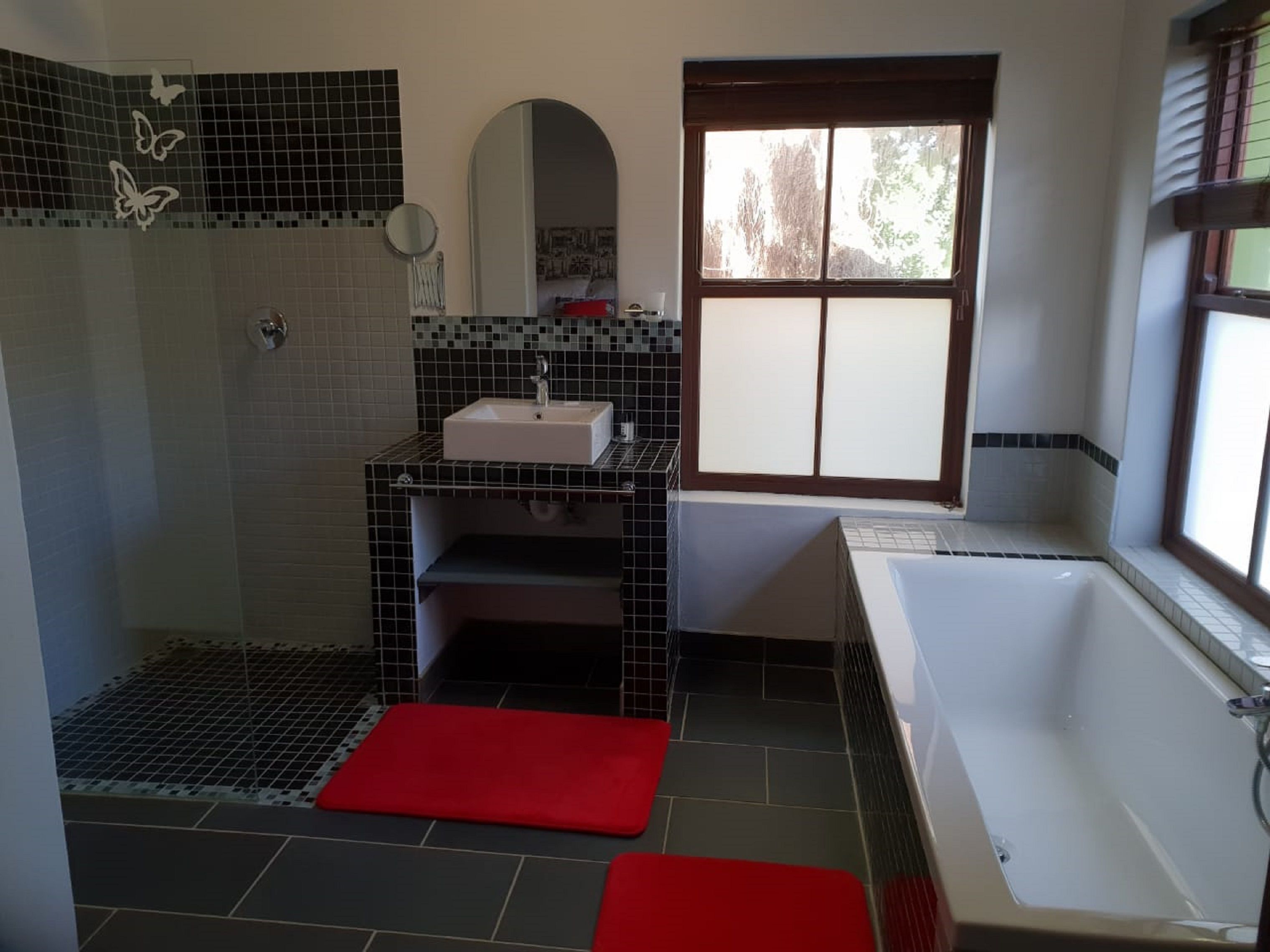 Une salle de bain avec une douche, un lavabo, un miroir et une fenêtre.