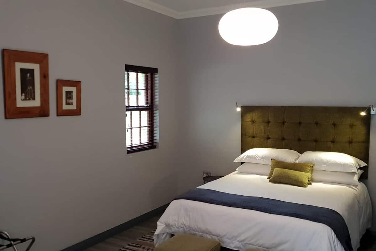 Une chambre avec un grand lit, une fenêtre et un luminaire rond.