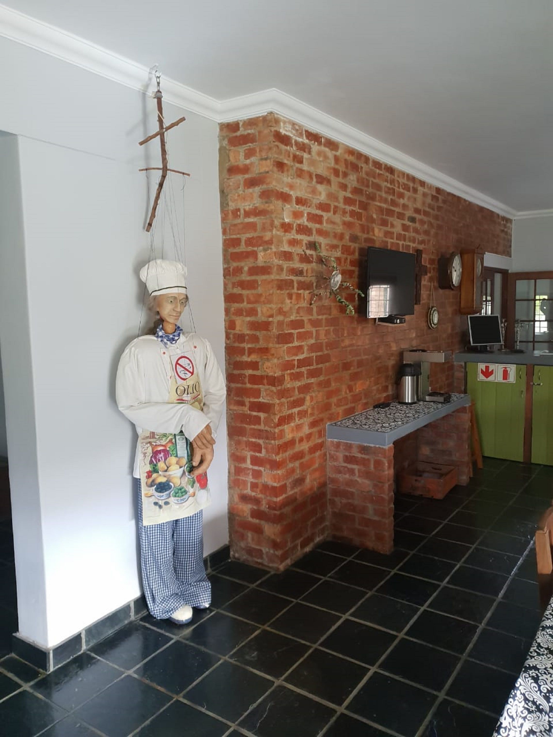 Une cuisine avec un mur en briques, un torchon suspendu, une cuisinière et un meuble vert.