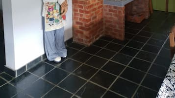 Une cuisine avec un mur en briques, un torchon suspendu, une cuisinière et un meuble vert.