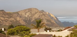 A mountain with a rocky surface and a town in the valley below. - Port Del Mar Luxury Guesthouse (Hermanus)