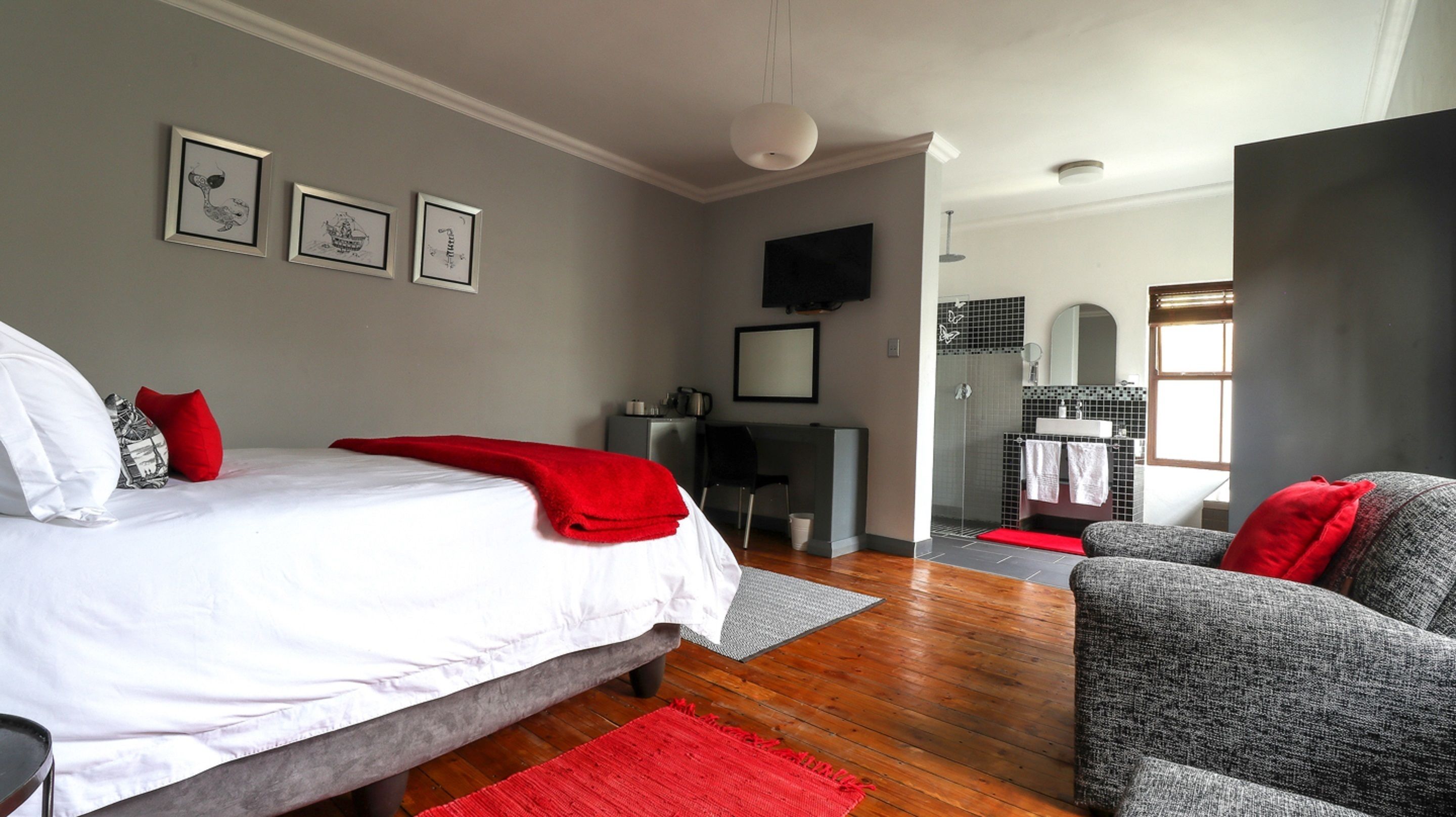 A modern bedroom with a bed, a desk, and a shower area.