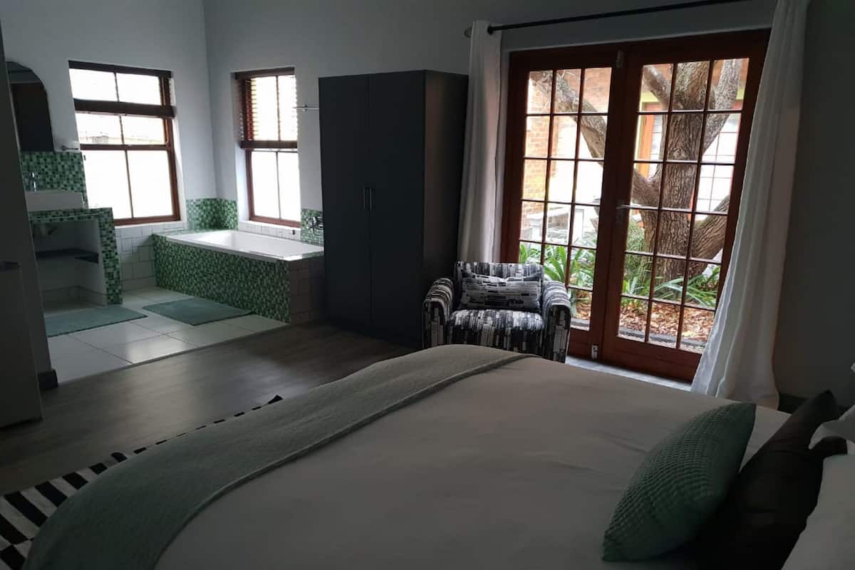 Une chambre à coucher avec un grand lit, une chaise, une armoire et une vue sur l’extérieur par une fenêtre.