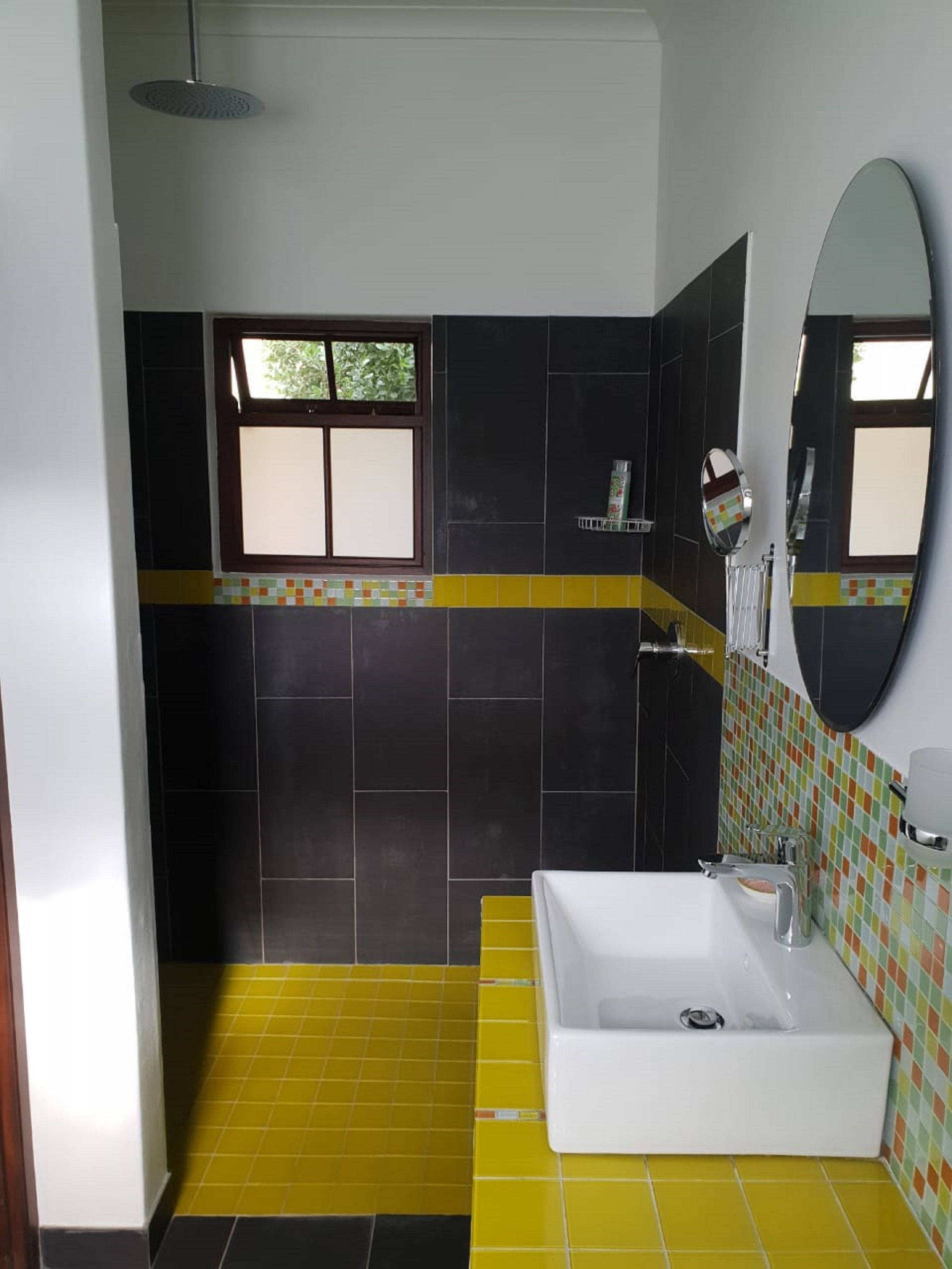 Un baño con una bañera blanca, un espejo y una ventana.