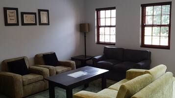 A living room with two sofas, a coffee table, and a floor lamp. There are three framed pictures on the wall.