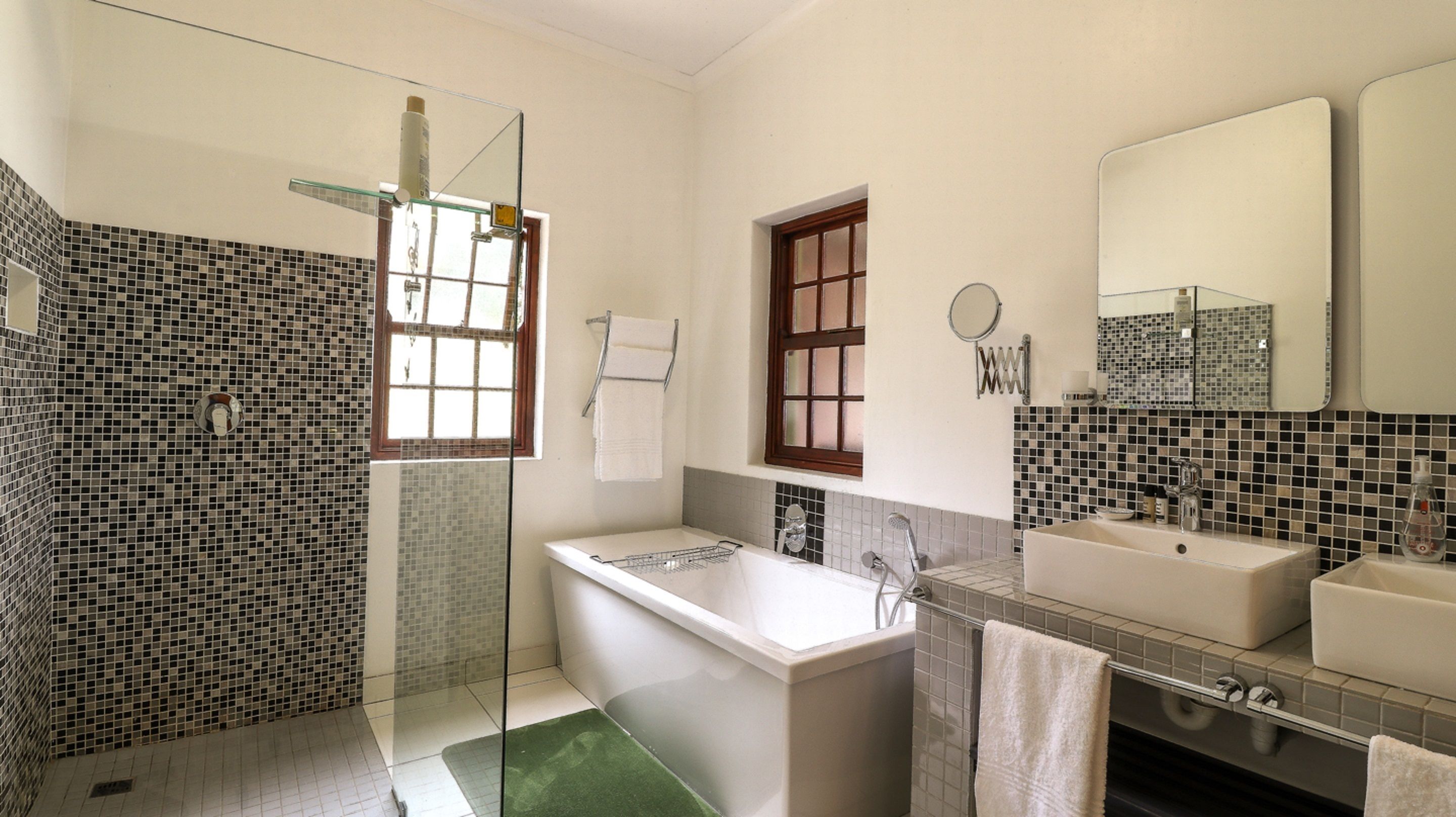 Un baño moderno con cabina de ducha de vidrio, bañera independiente y tocador con lavabo y espejo.