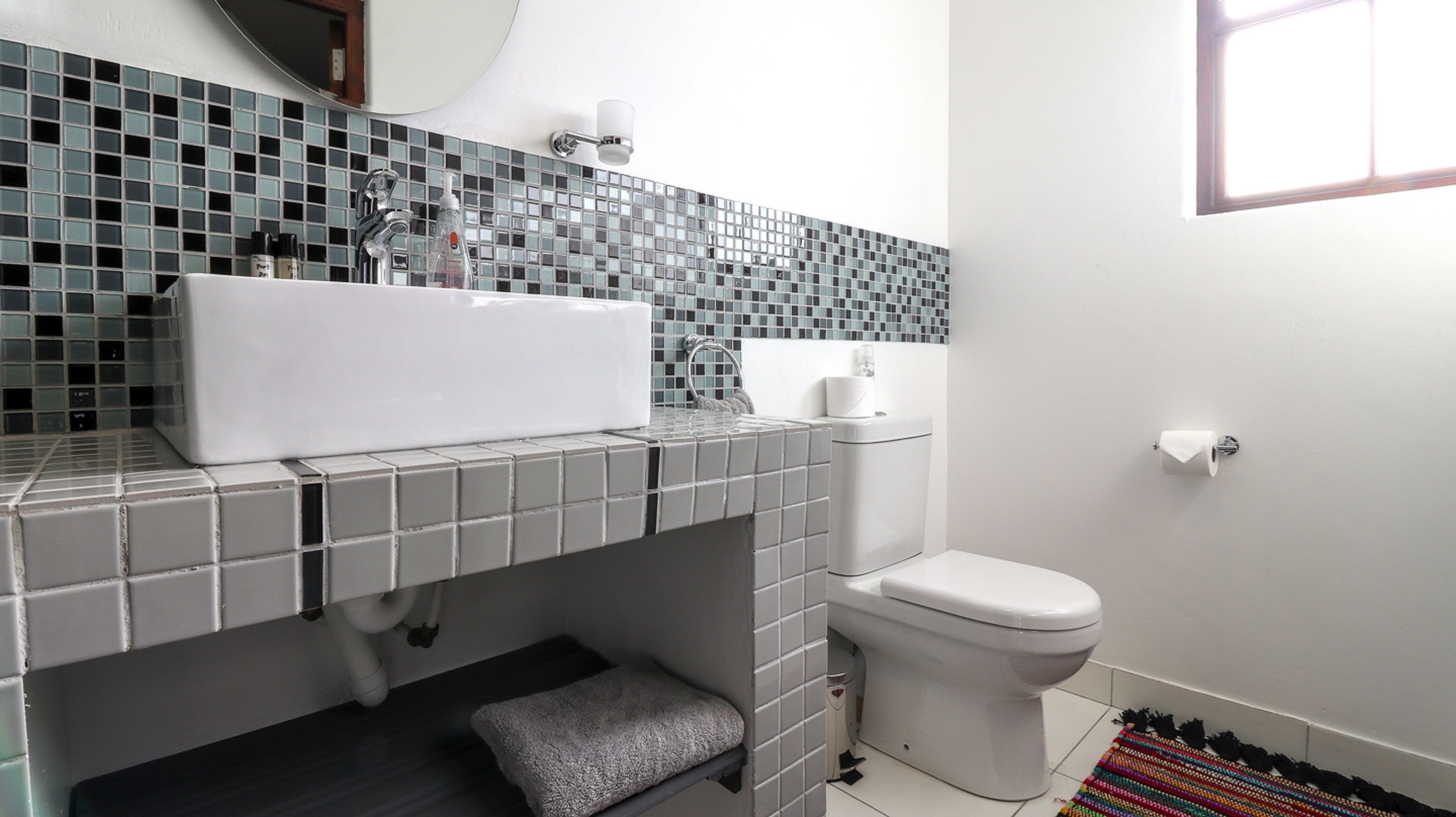A bathroom with a white sink, a toilet, and a tiled backsplash.