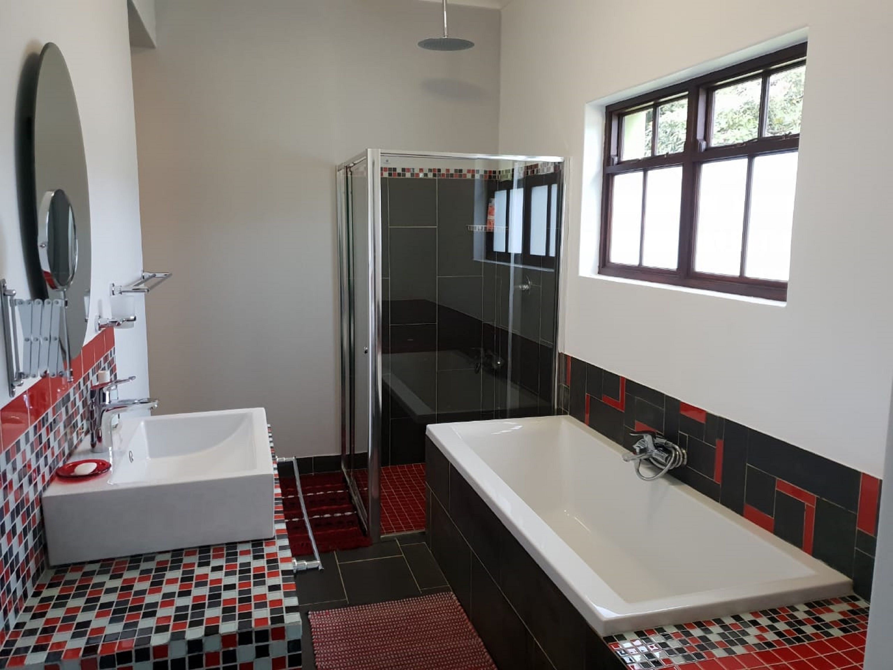 Un baño moderno con un lavabo blanco, una bañera grande y una ducha con mampara de vidrio.