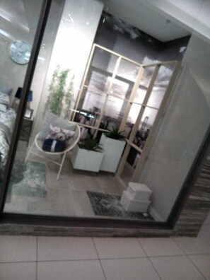 A modern living room with a glass partition, a white sofa, a small table, and a potted plant. - Rosebank Accommodation (Johannesburg)