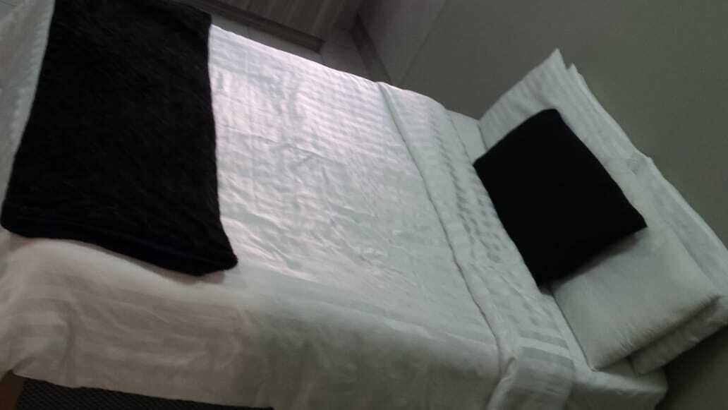 Un lit avec une literie blanche et un oreiller noir.