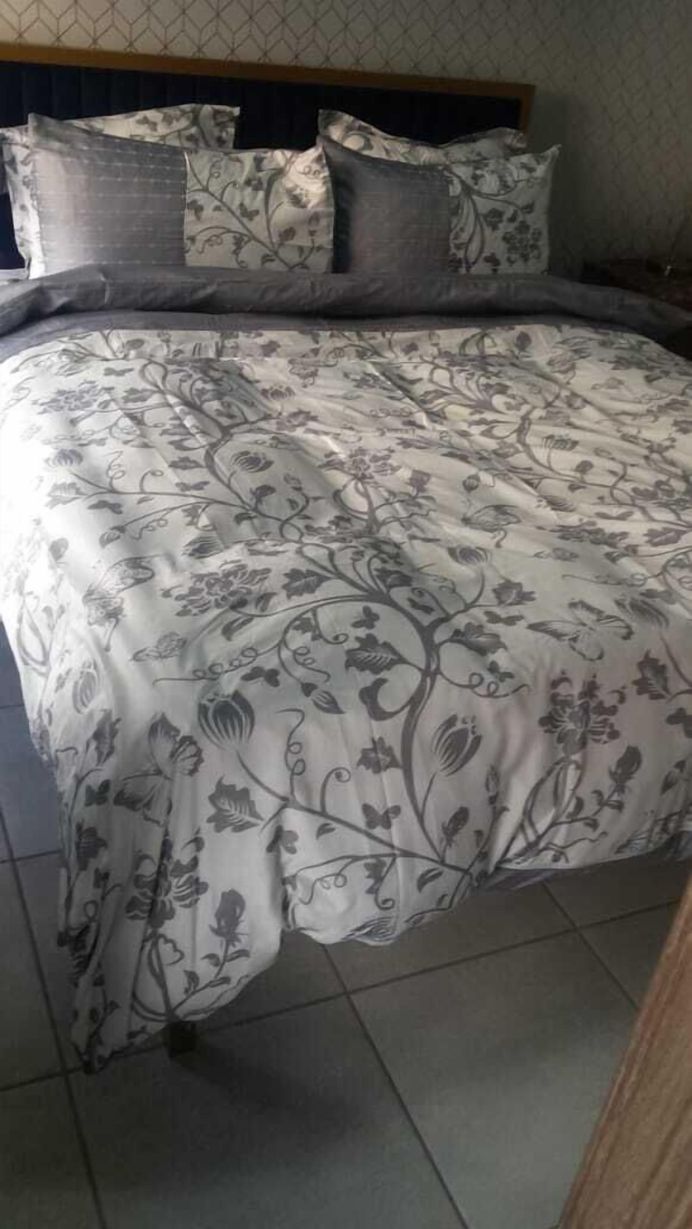 Een bed met een bloemenprint sprei en passende kussens.