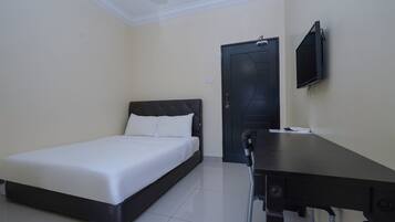 A bedroom with a bed, a desk, a chair, a television, and a door.