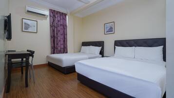 A hotel room with two beds, a desk, a chair, an air conditioner, and two framed pictures on the walls.