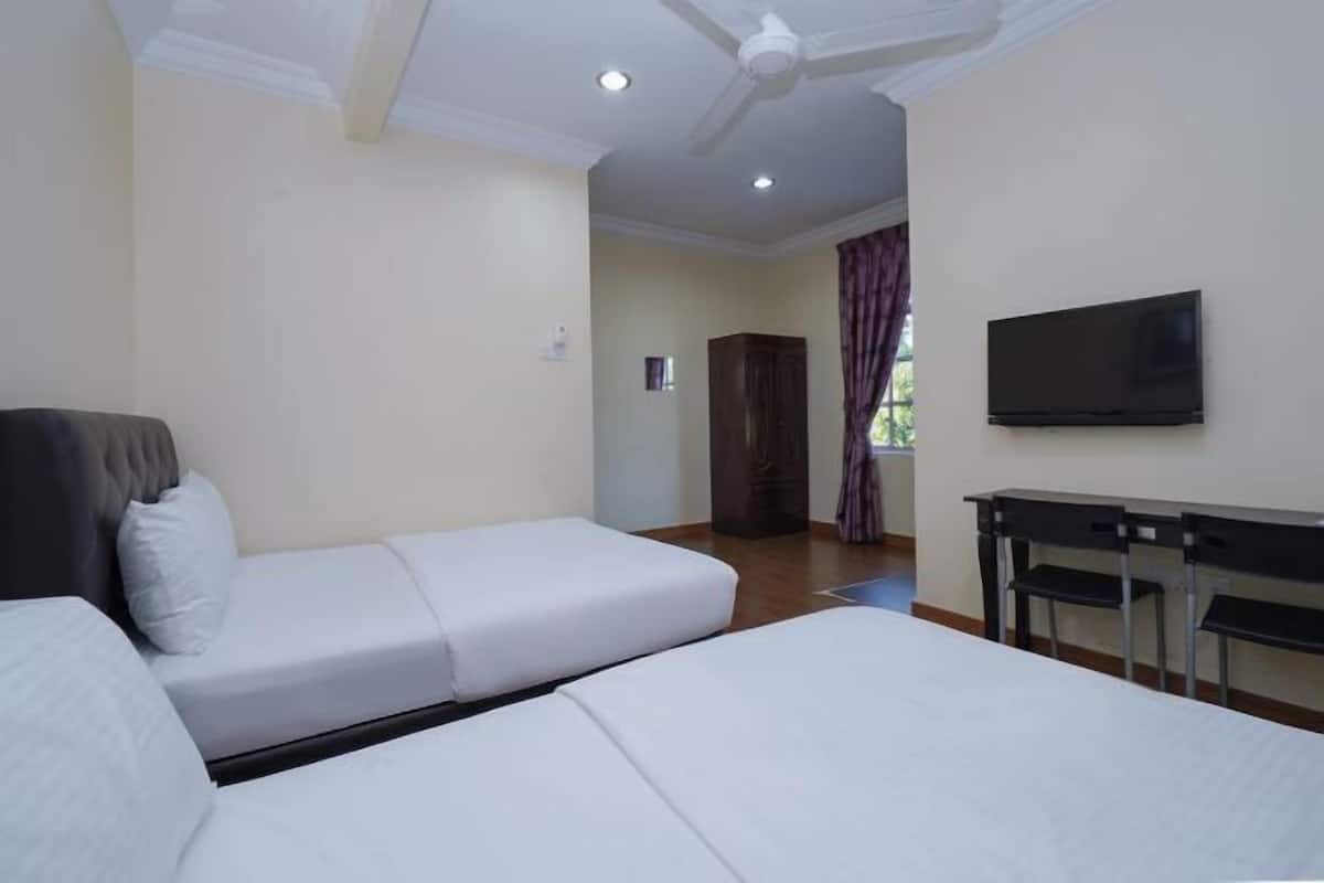 Ein Hotelzimmer mit Bett, Schreibtisch, Fernseher und Deckenventilator.